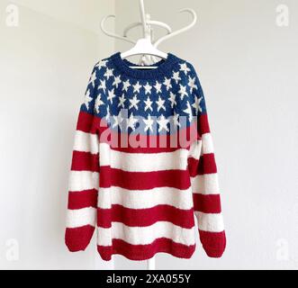 Photo of a USA Flag patriotic knitted wool red blue white sweater with stripes and stars in traditional icelandic pattern with its sleeves tied up han Stock Photo