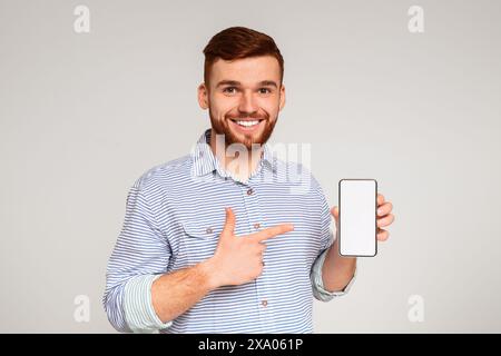 Smiling millennial man holding latest slim cellphone Stock Photo