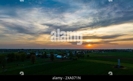 The sun setting over an open field with a cloudy sky Stock Photo