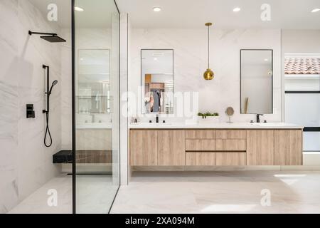 A bathroom with twin sinks, marble countertops, and glass shower enclosures Stock Photo