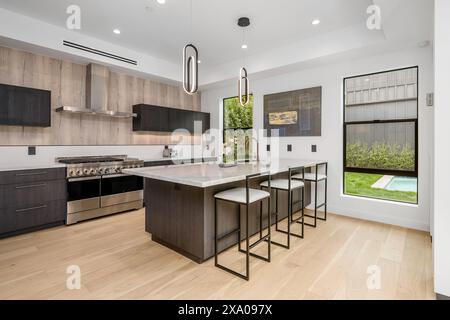 Modern kitchen with a central island and stools beside the stove Stock Photo