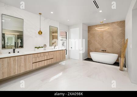 Spacious bathroom with dual sinks, wooden cabinets, and a large white bathtub Stock Photo