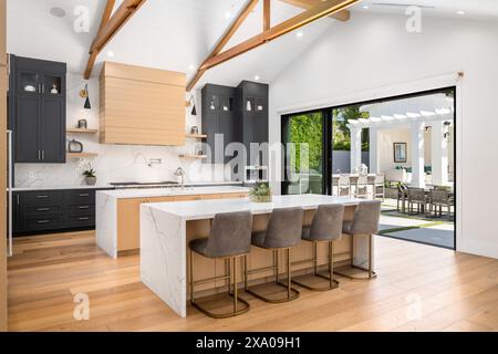 A spacious kitchen with black and white countertops and a white island Stock Photo