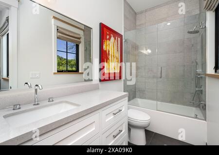 A spacious bathroom with a white bathtub, sink, and shower Stock Photo
