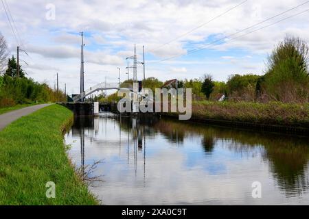 A lock and pedestrian bridge over the canal, with reflection in the water in Schoten, Antwerp, Belgium Stock Photo
