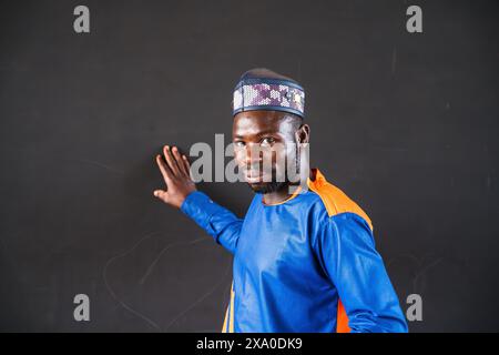 A teacher in African robe against a blackboard for an opening of a primary school with a German organization Stock Photo