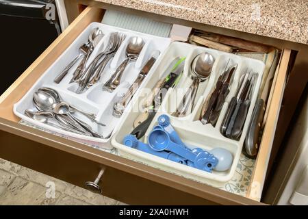 Horizontal shot of a messy and cluttered silverware drawer in the home of some elderly people. Stock Photo