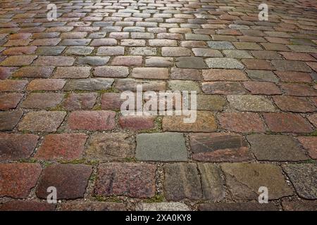 A background of a sidewalk made of square-shaped natural stone of light lilac, gray color. Stock Photo