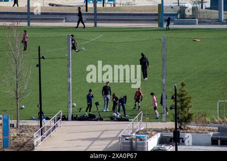 A group of individuals engaged in a soccer game on a grass field Stock Photo