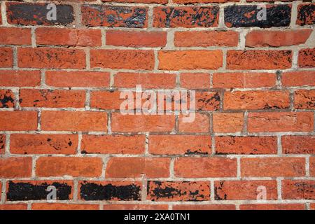 A weathered old red brick wall with peeling paint and cracks. Stock Photo