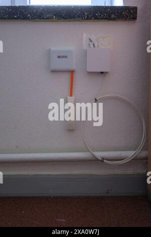 a newly installed fiber optic connection hangs on the wall Stock Photo