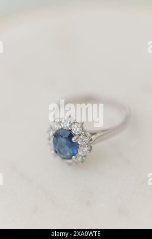 An oval sapphire and round diamond engagement ring on marble table Stock Photo