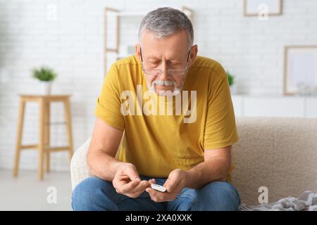 Senior man checking blood sugar level at home. Diabetes concept Stock Photo