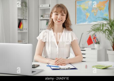 Female travel agent sitting at table in office Stock Photo