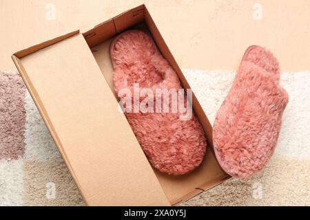 Pair of red soft slippers in box on carpet. Top view Stock Photo