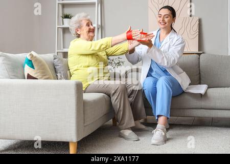 Senior woman with stretching band and physical therapist at home Stock Photo