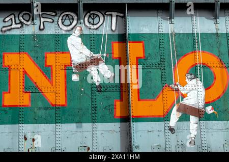 The bridge graffiti art of two men on a swing painting the wall Stock Photo