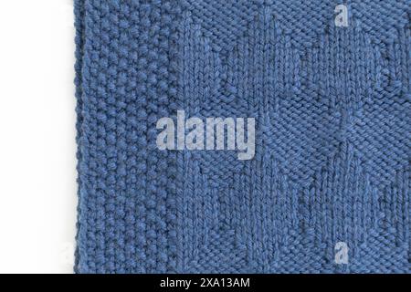 Close-up photography of an edge of a blue knitted blanket in harlequin knitting pattern in a basket on a white background Stock Photo