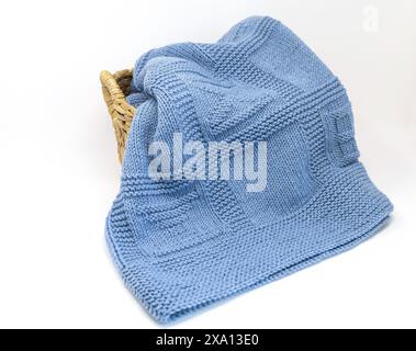 photography of a blue wool textured hand-knitted blanket in geometric knitting pattern in a basket isolated on a white background Stock Photo