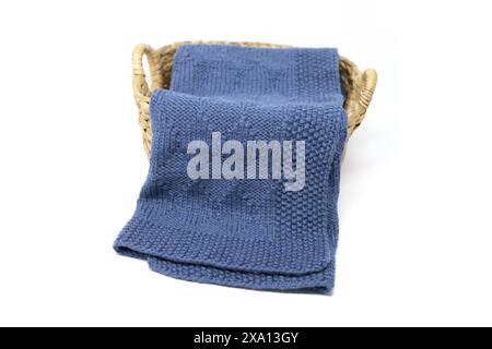 Navy blue wool knitted blanket in harlequin knitting pattern in a basket on a white background Stock Photo
