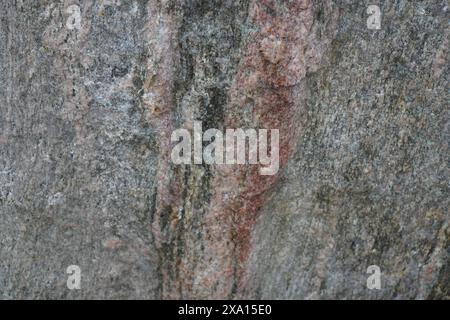 A big rock surrounded by green rocks with a black skateboard on top Stock Photo