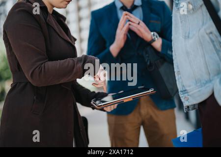 Professional colleagues using gadgets during a business meeting outdoors Stock Photo
