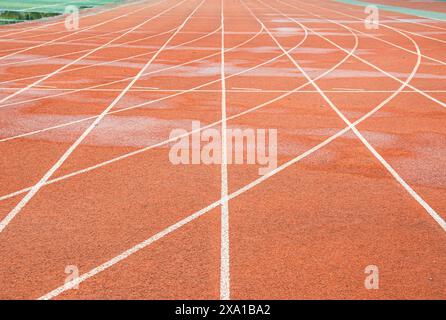 The bright red runway interweaves the straight white trajectory with the curved white trajectory. Stock Photo