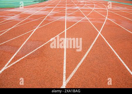 The bright red runway interweaves the straight white trajectory with the curved white trajectory. Stock Photo