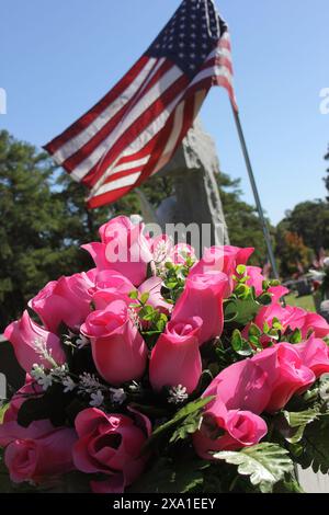 The pink roses and American flag on grave at Rose Hill Cemetery in Tyler TX Stock Photo