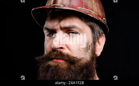 Closeup portrait of professional builder or miner with dirty face in protective helmet. Heavy industry and mining concept. Fatigued serious mechanical Stock Photo