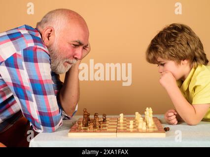 Chess competition. Grandfather and grandson playing chess. Child boy play chess with granddad. Brain development and logic concept. Little boy thinkin Stock Photo