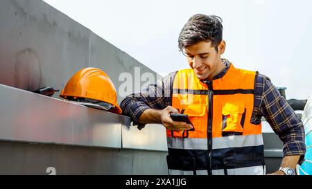 An engineer in a safety vest using his phone at a construction site. Stock Photo