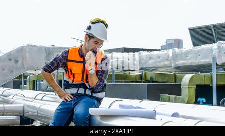 An engineer talking on a walkie-talkie at a construction site. Stock Photo