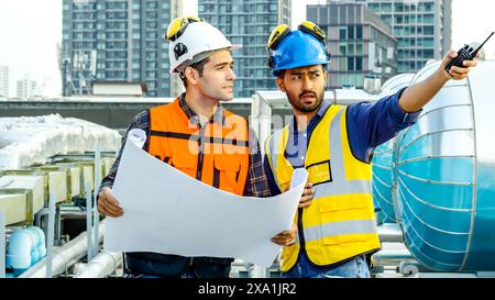 The two construction workers in safety gear examining blueprints and discussing. Stock Photo