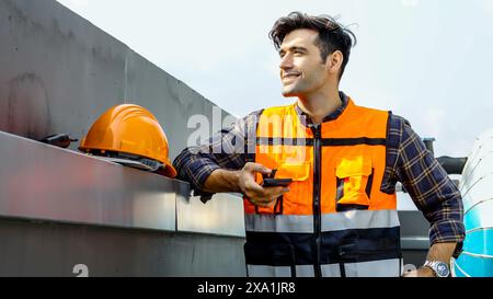 A man stands in front of a metal wall with a helmet on shoulder. Stock Photo