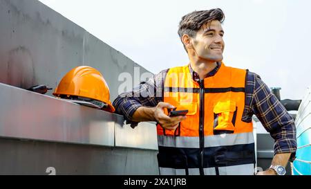 An engineer in a safety vest using his phone at a construction site. Stock Photo