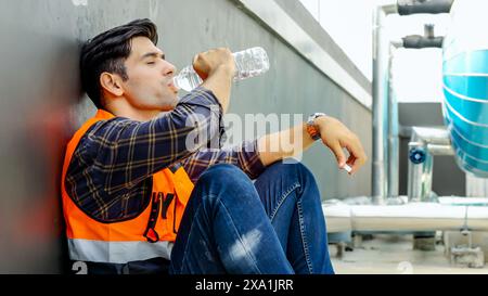 A man in a safety vest hydrates with a water bottle. Stock Photo