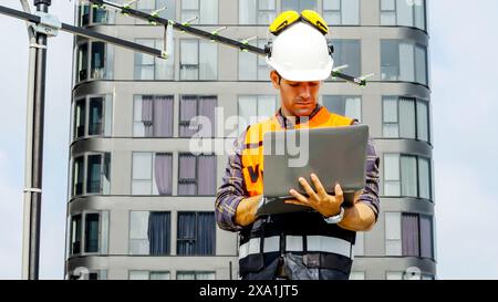 An engineer working on a laptop at a building site. Stock Photo