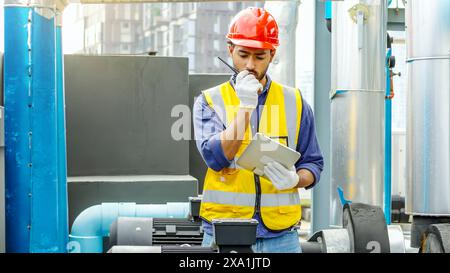 Worker in safety gear with laptop and walkie-talkie on construction site Stock Photo