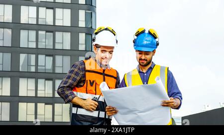 The two men reviewing blueprints for construction materials on a rooftop. Stock Photo