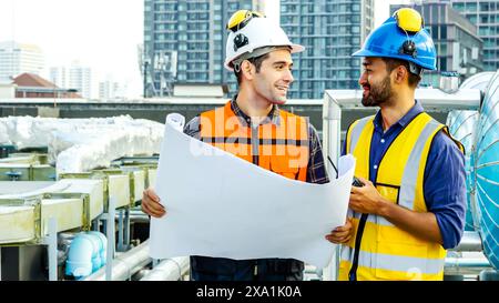 The two men reviewing blueprints for construction materials on a rooftop. Stock Photo