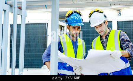 The two men reviewing blueprints for construction materials on a rooftop. Stock Photo