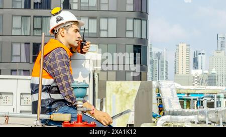 Worker in safety gear with laptop and walkie-talkie on construction site Stock Photo