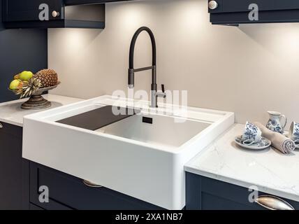 Modern black faucet and white kitchen sink in new kitchen with gray cabinets Stock Photo