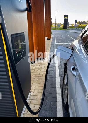 An electric vehicle being refueled at a charging station Stock Photo