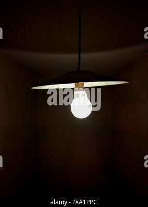 A light bulb glowing in a dark room. Stock Photo