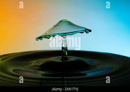 The water drops forming a mushroom against a colorful backdrop. Stock Photo