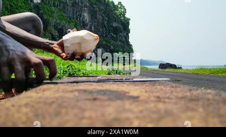 View of an African man with a machete cutting a coconut.Sao Tome,Africa Stock Photo