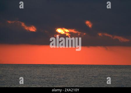 The sun setting over the ocean at dusk Stock Photo