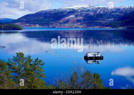 A Fish farm on the serene waters of a Norwegian fjord near Angvik, Norway Stock Photo